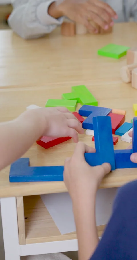 Vertical close view follows young pupil hands arranging colorful block pieces on Stock Footage 336071535