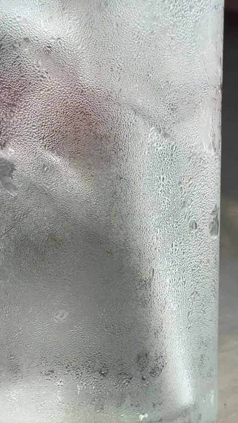 Vertical Close Up View Of Iced Water Glass With Condensation Droplets On Hot Day Stock Footage 345710437
