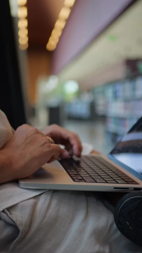 Vertical Close-Up View Of Person Using Laptop Inside Library Environment... 動画素材 334437348