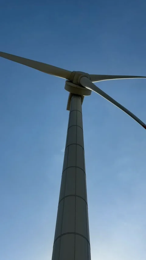 Vertical close view of the upper part of a wind turbine rotating against a 動画素材 329372597