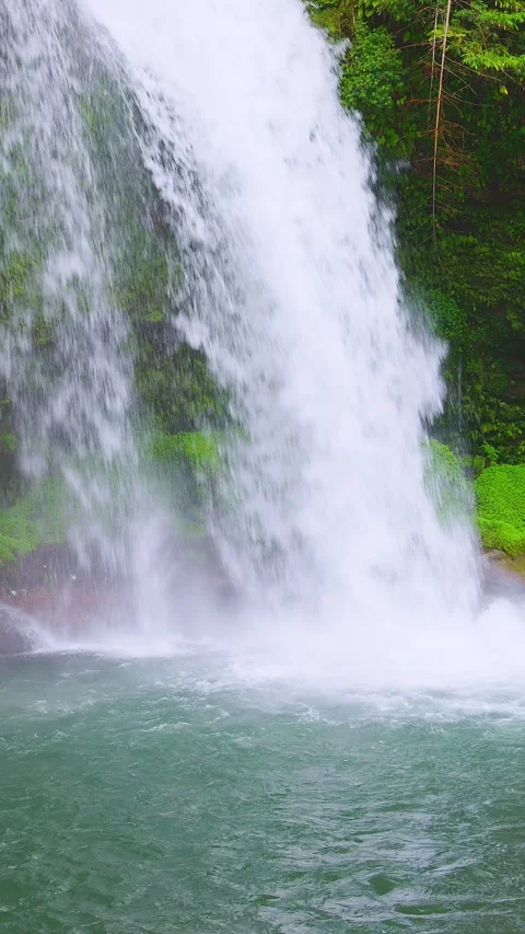 Vertical close up of waterfall splashing into clear emerald plunge pool 動画素材 341806363