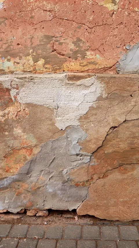Vertical close-up of a weathered wall with peeling plaster, cracked render, and Stock Footage 333653991