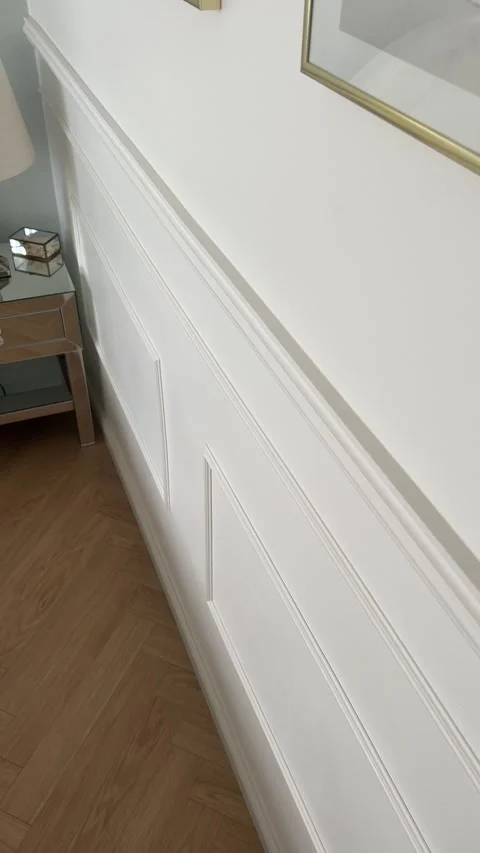 Vertical close up of white classic wall molding with oak herringbone floor Stock-Footage 346486311