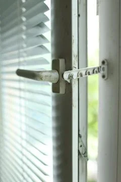 Vertical close up of a white pvc window handle with a metal safety comb Stock Photos