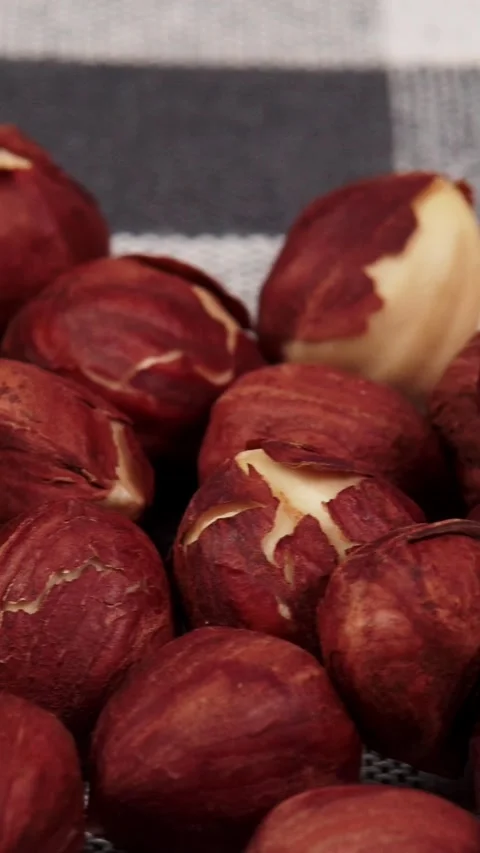 Vertical close up of whole peeled hazelnuts pile on fabric background 库存影片 346639593