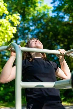 Vertical close up of woman doing pull ups outdoors 写真素材