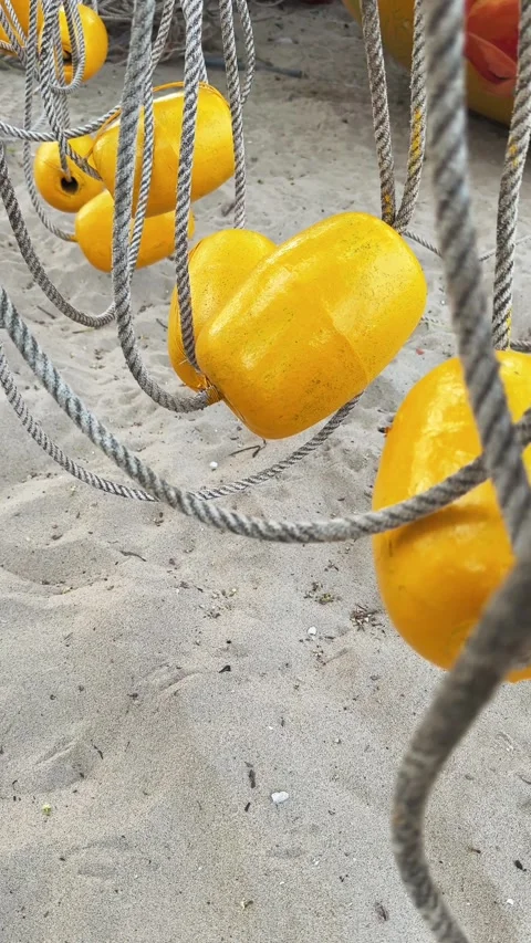 Vertical close up of Yellow Beach Buoys on Rope hanging above Sand on the beach. Vidéo 339638892
