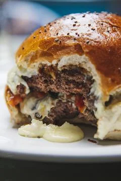 A vertical closeup of a delicious cheeseburger with a bite mark in it on a bl Foto stock