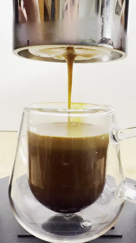Vertical - Closeup of espresso coffee being delivered to fill a glass cup. Stock Footage 302367013