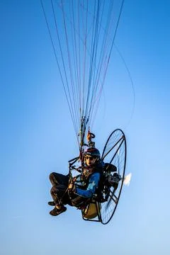 Vertical closeup of a man doing a paramotor flight paragliding against a blue sk Stock Photos