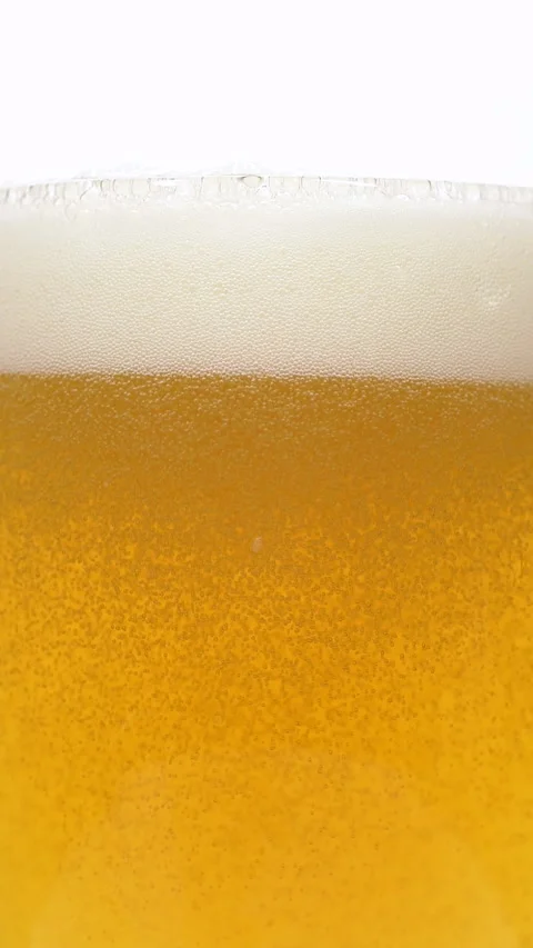 Vertical closeup of pouring beer with foam and bubbles in slow motion over white Stock Footage 269878005