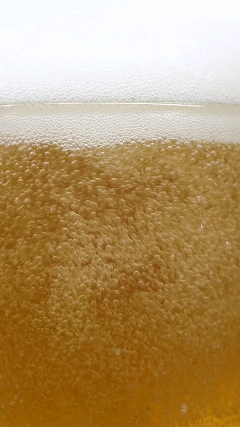 Vertical closeup of pouring beer with foam and bubbles in slow motion over white Stock Footage 273546722