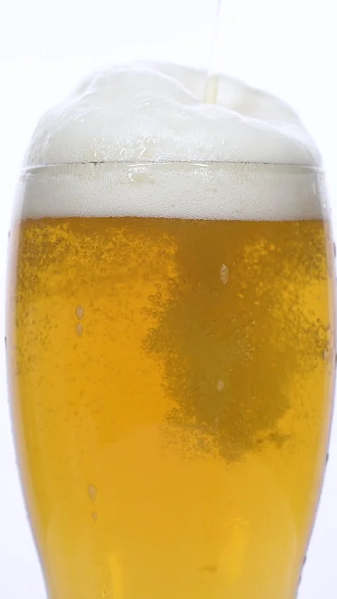 Vertical closeup of pouring beer with foam and bubbles in slow motion over white Stock Footage 274119133
