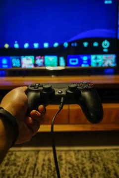 Vertical closeup of a PS4 black controller DualShock 4 in a gamer's hand Stock Photos