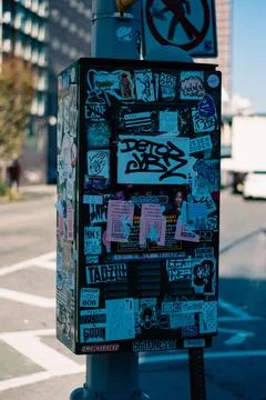 Vertical closeup of a rectangular stickered object on the street sunlit blurred 스톡 사진