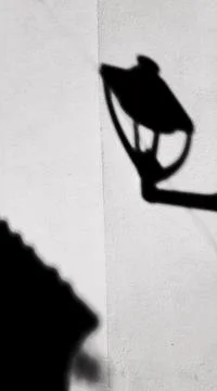 Vertical closeup of the shadow of a lantern on a white-colored wall Stock Photos