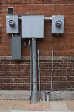 Vertical closeup shot of electrical wire boxes on a brick wall Stock Photos