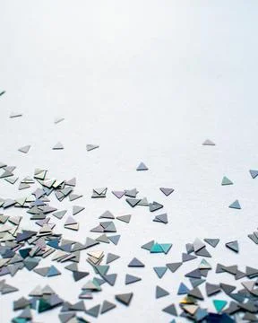 Vertical closeup shot of sparkly triangular confetti on a white surface Foto stock