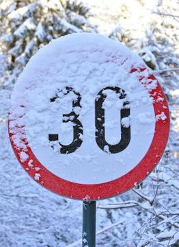 Vertical closeup shot of the speed limit sign covered in snow Stock Photos