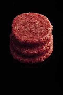 Vertical closeup shot of a stack of raw burger patties on a black surface Foto stock