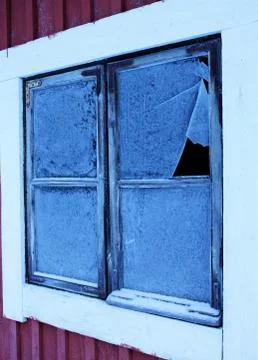 Vertical closeup of a square window with a broken glass on a red and white wa Stock Photos