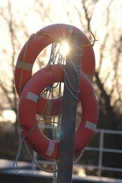 Vertical closeup of two life-saving float rings tied to a wooden plank Foto stock