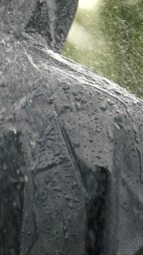 Vertical closeup video of unrecognizable person in heavy rain, man in black coat Stock Footage 274045396