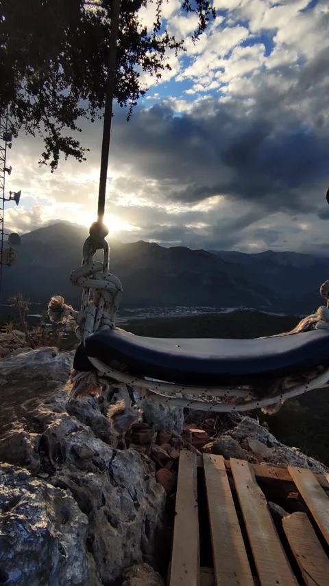 Vertical closeup view of empty swing hanging on edge of the rock over precipice Video stock 344043126