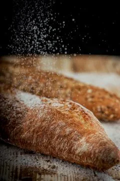 Vertical closeup view of two fresh crunchy baguettes with raining flour on th Stock Photos