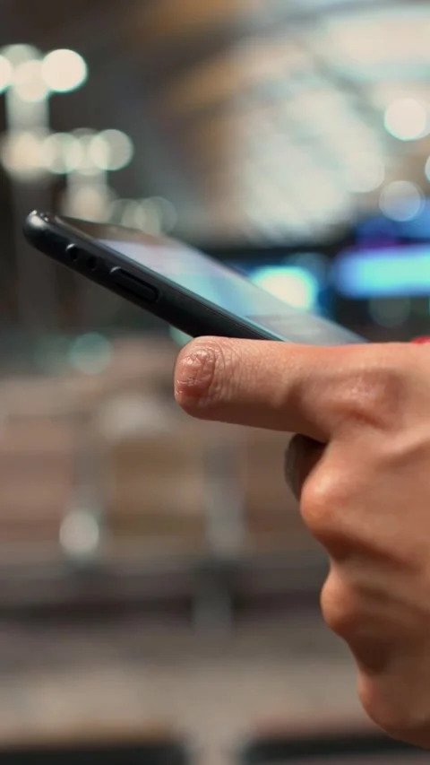 Vertical closeup of woman hands using a smartphone in an airport terminal Stock Footage 307571474