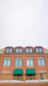Vertical Cloudy sky and string lights over a building with brick wall and snowy Stock Photos
