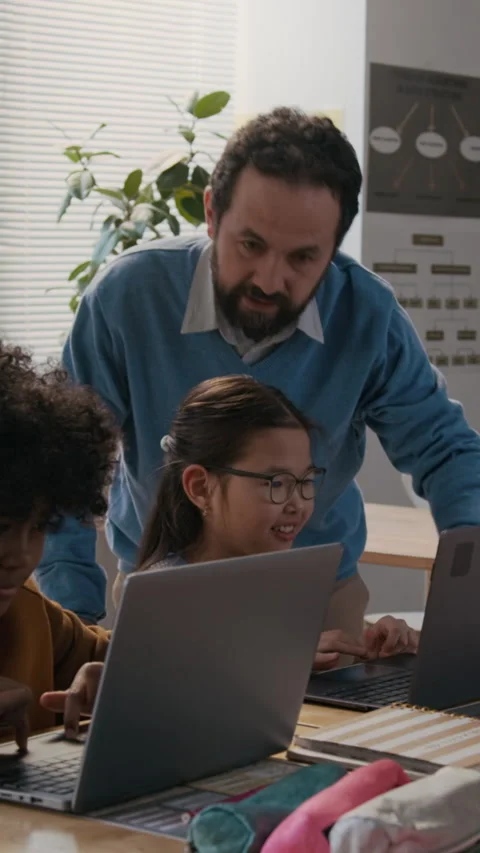 Vertical of Coding Teacher Assisting Diverse Schoolkids Working on Laptops Stock Footage 307092392