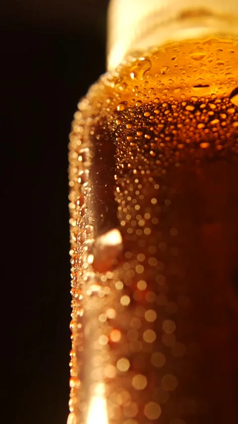 Vertical composition of a brown glass bottle covered in water droplets, glowing Stock Footage 313485786