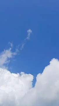 Vertical composition of a clear blue sky with soft white clouds, Foto stock