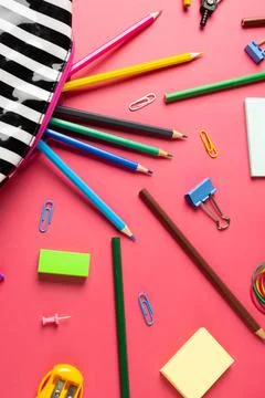 Vertical composition of crayons in striped case, clips and sharpener on pink Stock Photos