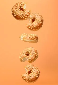 Vertical composition of levitating bitten caramel donuts with nut crumbs Stock Photos