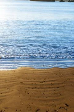 Vertical composition water rippling as it washes into golden sand beach edg.. Stock Photos