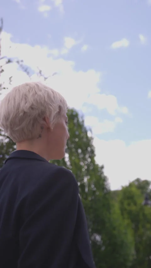 Vertical of Confident Woman with Blonde Pixie Haircut Walking on cloudy day Video stock 208777980