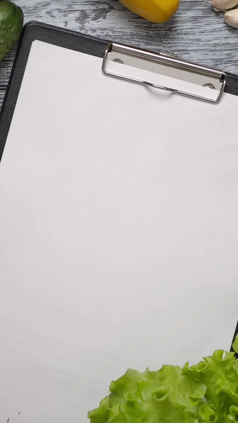 Vertical of Cook taking lettuce from table with blank paper clipboard Stock Footage 276816965