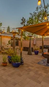 Vertical Cozy stone patio with string of lights over a covered seating and Stock Photos