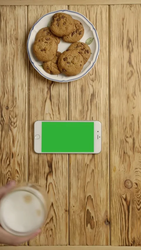 Vertical of Crop person drinking coffee and eating cookies near smartphone Stock Footage 276930153