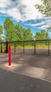 Vertical crop Private gate at a secured property with red traffic poles on the Foto stock