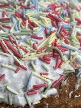 Vertical cropped close up of multi-colored sprinkles on cake frosting Stock Photos