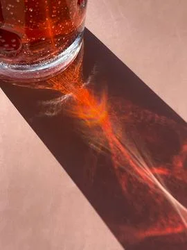 Vertical cropped close up of sunlight shining through red liquid in a glass,  Stock Photos