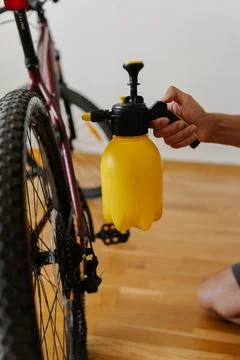Vertical cropped shot of cyclist using yellow handheld water sprayer to clean Stock Photos
