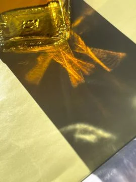Vertical cropped shot of sunrays beaming through a bottle with yellow liquid, Stock Photos