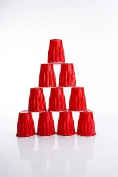Vertical of a cup pyramid made of red disposable plastic cups against a white ba Foto stock
