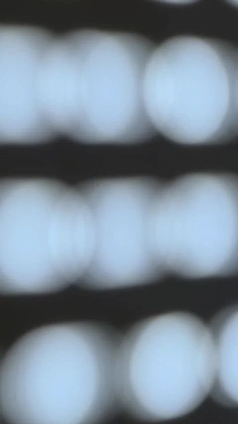 Vertical defocused 4K video. Blurred round white lights bokeh on dark wall Stock Footage 346425625