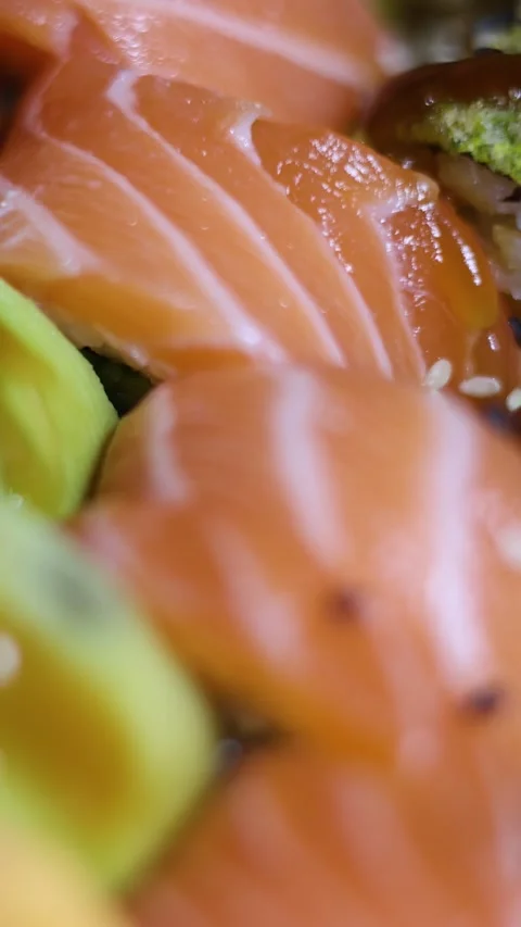 Vertical defocused video close up. Plate of fresh salmon sushi spins Stock Footage 311411874