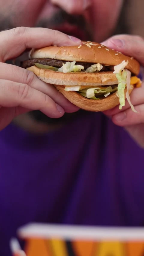 Vertical defocused video. Man with beard eats Big Mac burger Stock Footage 341275339